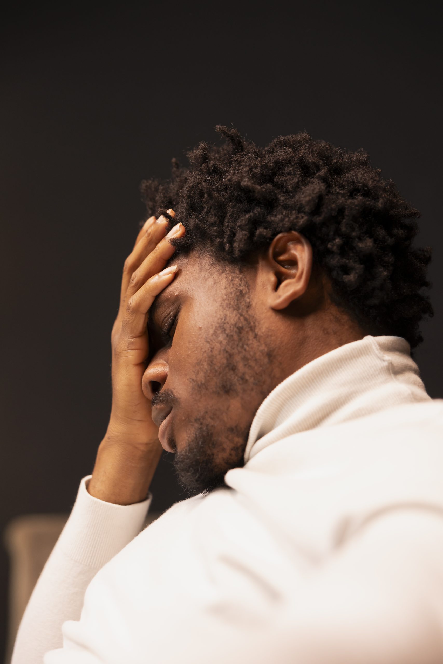 Man holding his head while looking anxious and stressed, reflecting emotional pressure and mental health concerns